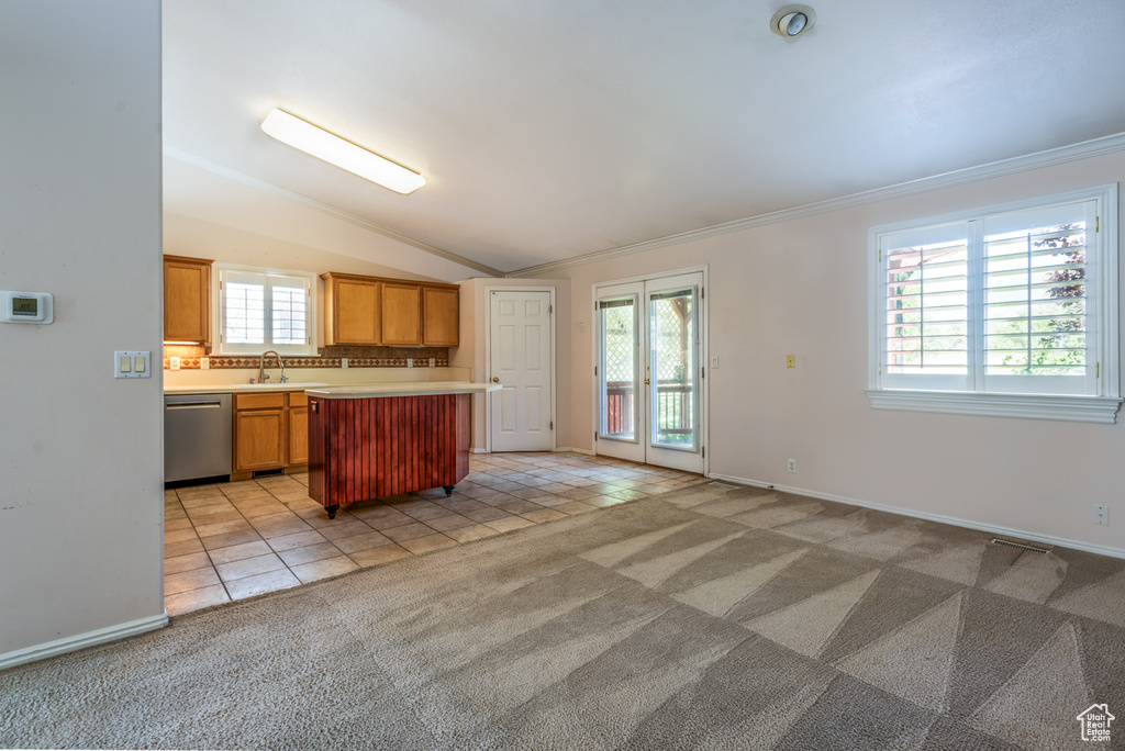 Kitchen with stainless steel dishwasher, light countertops, light carpet, crown molding, and light tile patterned flooring