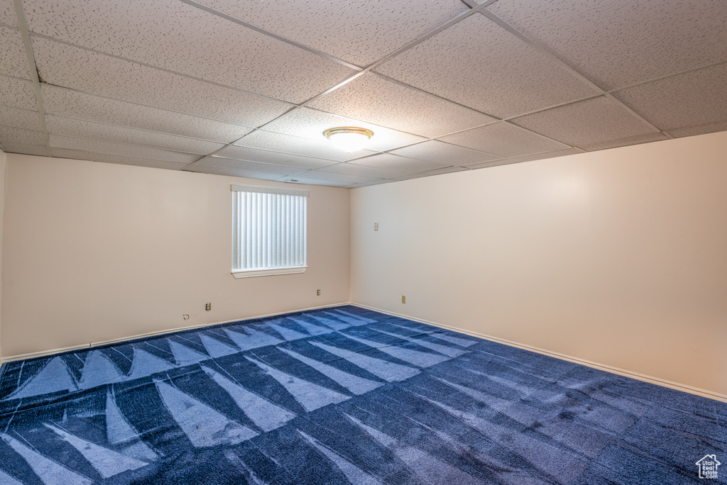 Empty room featuring a drop ceiling and carpet flooring