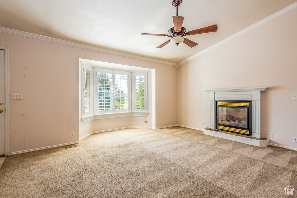 Unfurnished living room with carpet flooring, a ceiling fan, a glass covered fireplace, ornamental molding, and lofted ceiling