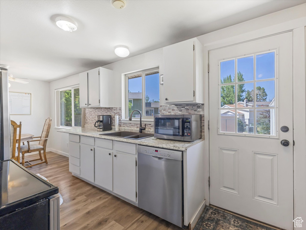 Kitchen with dishwashing machine, stainless steel microwave, range with electric cooktop, tasteful backsplash, and light wood-style floors