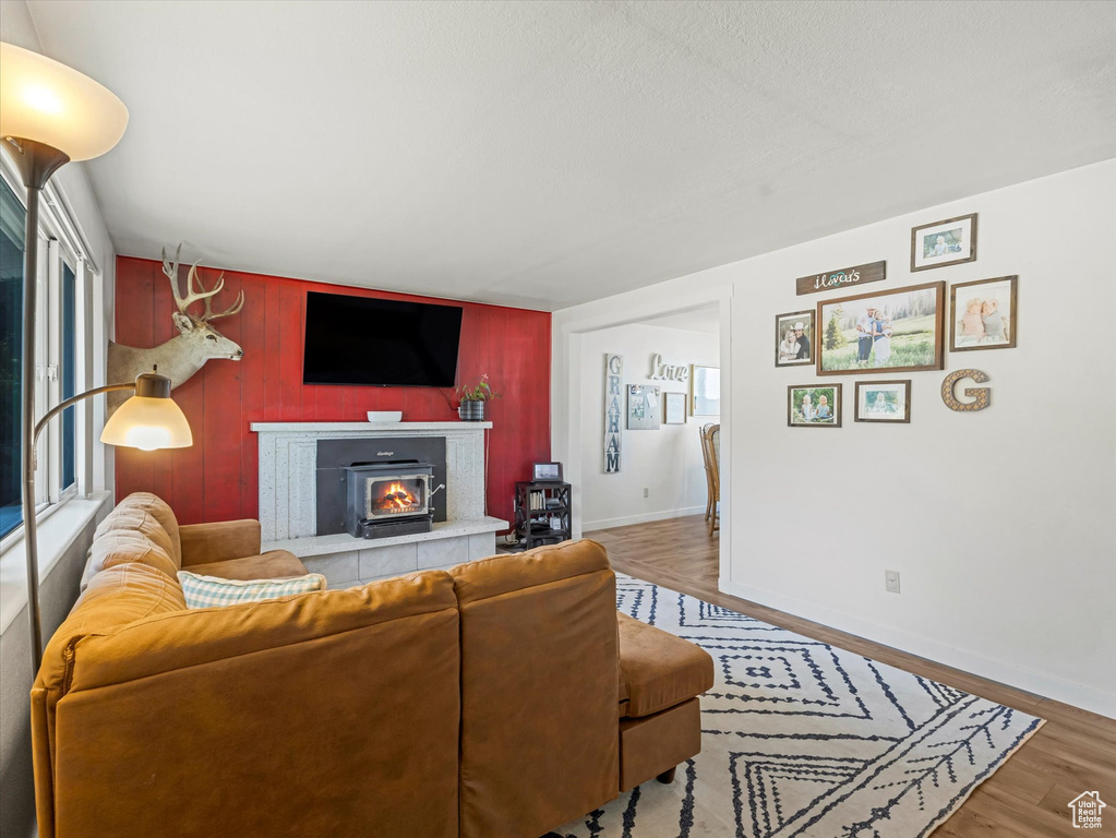 Living room with wood finished floors, wooden walls, and a fireplace