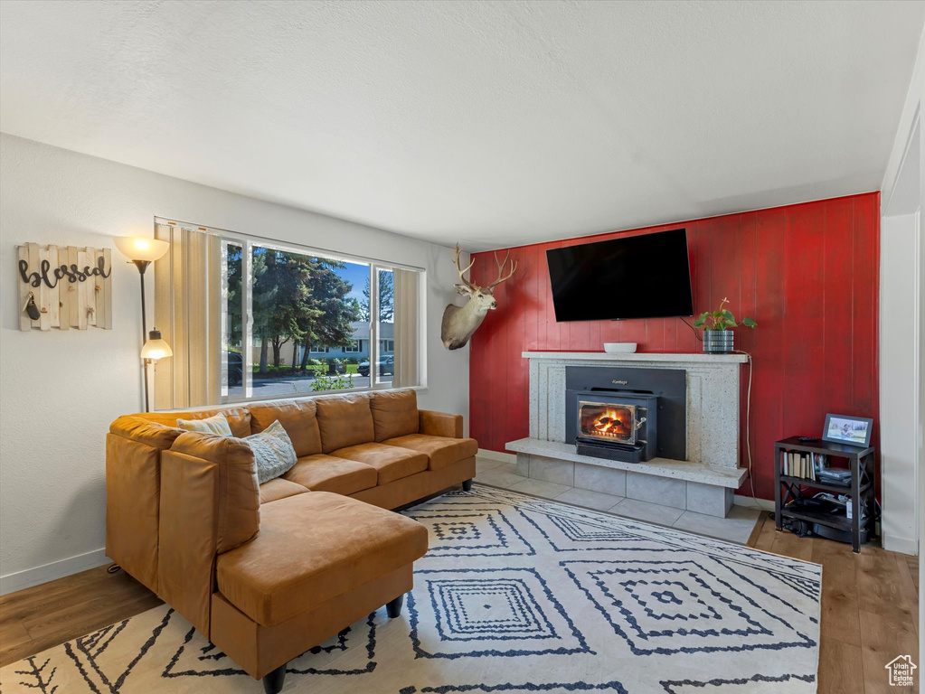 Living room featuring a tile fireplace, wood finished floors, and wood walls