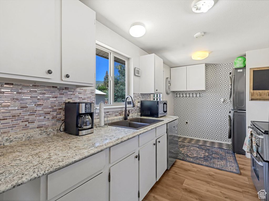Kitchen featuring stainless steel dishwasher, refrigerator, stove, white cabinets, and light wood-type flooring