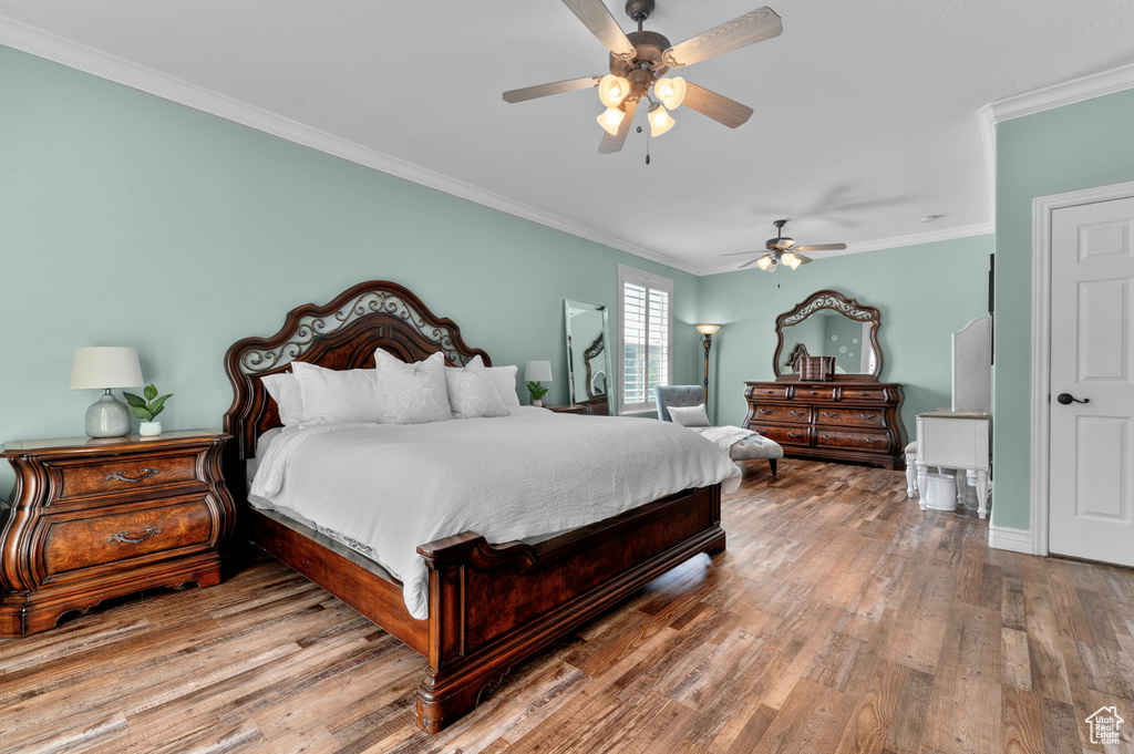 Bedroom with crown molding, wood finished floors, and a ceiling fan