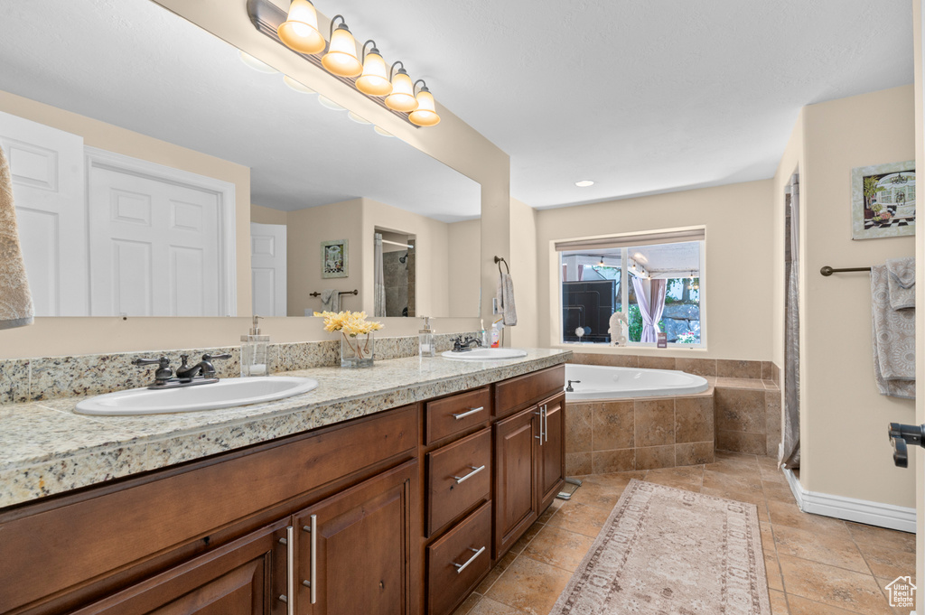 Full bath featuring double vanity, a stall shower, a bath, and tile patterned floors