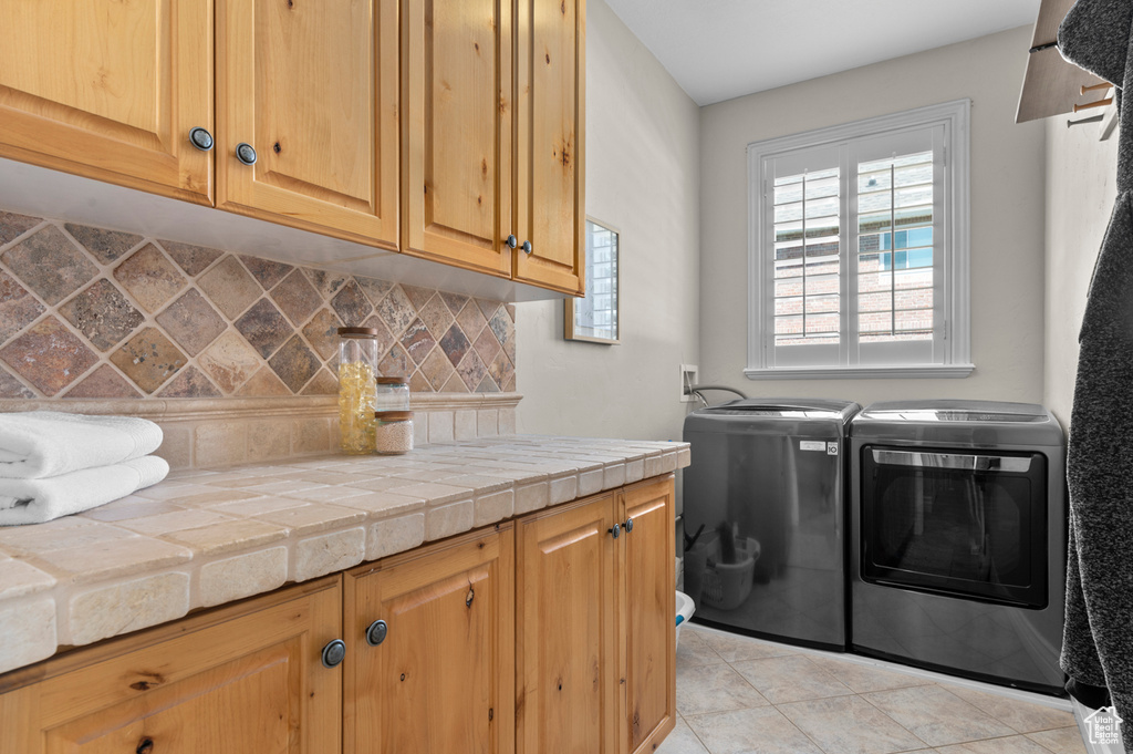Laundry room with washer and dryer, cabinet space, and light tile patterned floors