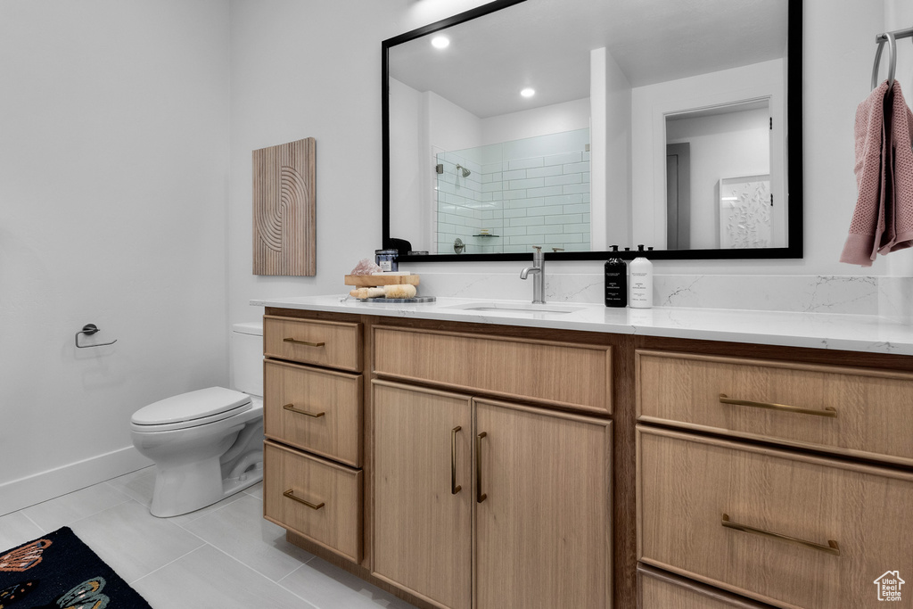 Bathroom with vanity, tiled shower, and tile patterned flooring