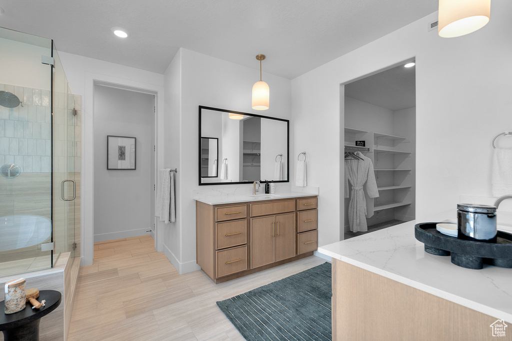 Bathroom with a stall shower, vanity, a walk in closet, recessed lighting, and wood finished floors