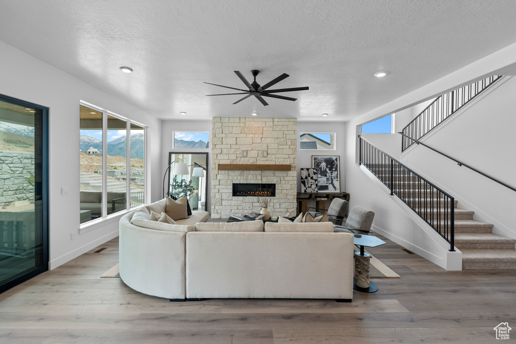 Living room featuring ceiling fan, a fireplace, stairway, wood finished floors, and recessed lighting