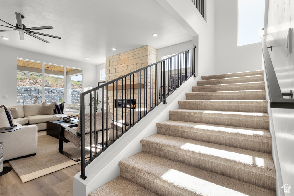 Staircase with wood finished floors, ceiling fan, and recessed lighting