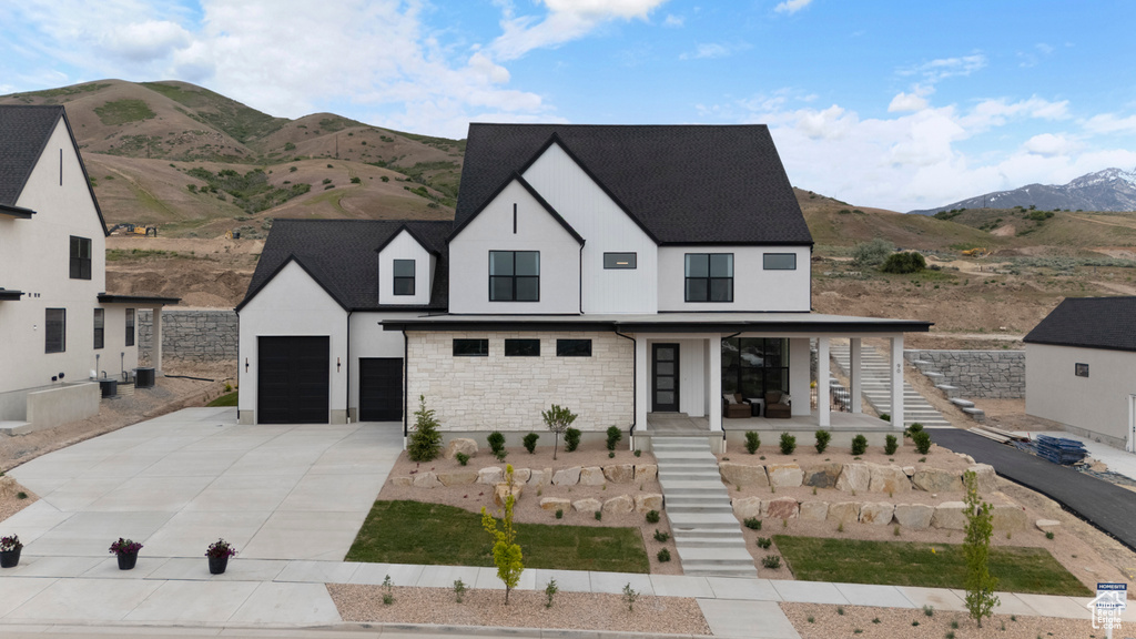 Modern farmhouse style home featuring driveway, a porch, stairs, stucco siding, and a mountain view