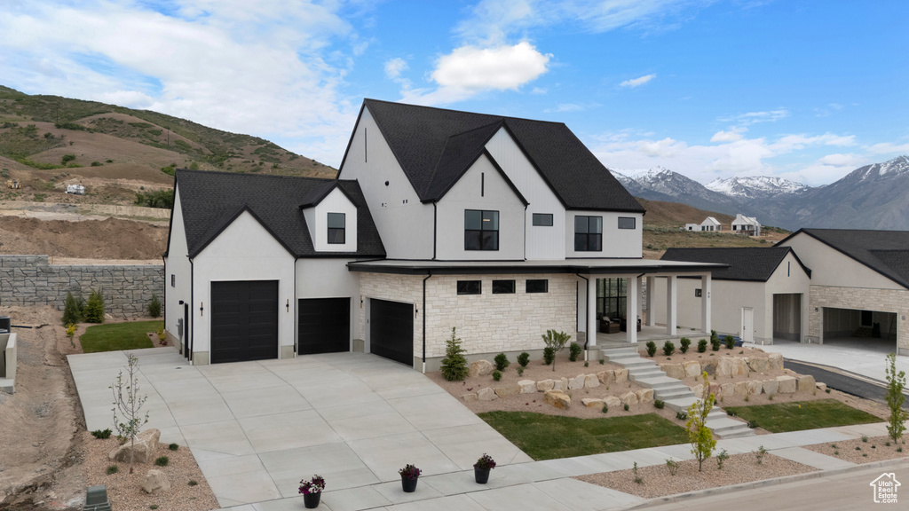 Modern inspired farmhouse with a mountain view, stucco siding, stone siding, a garage, and concrete driveway