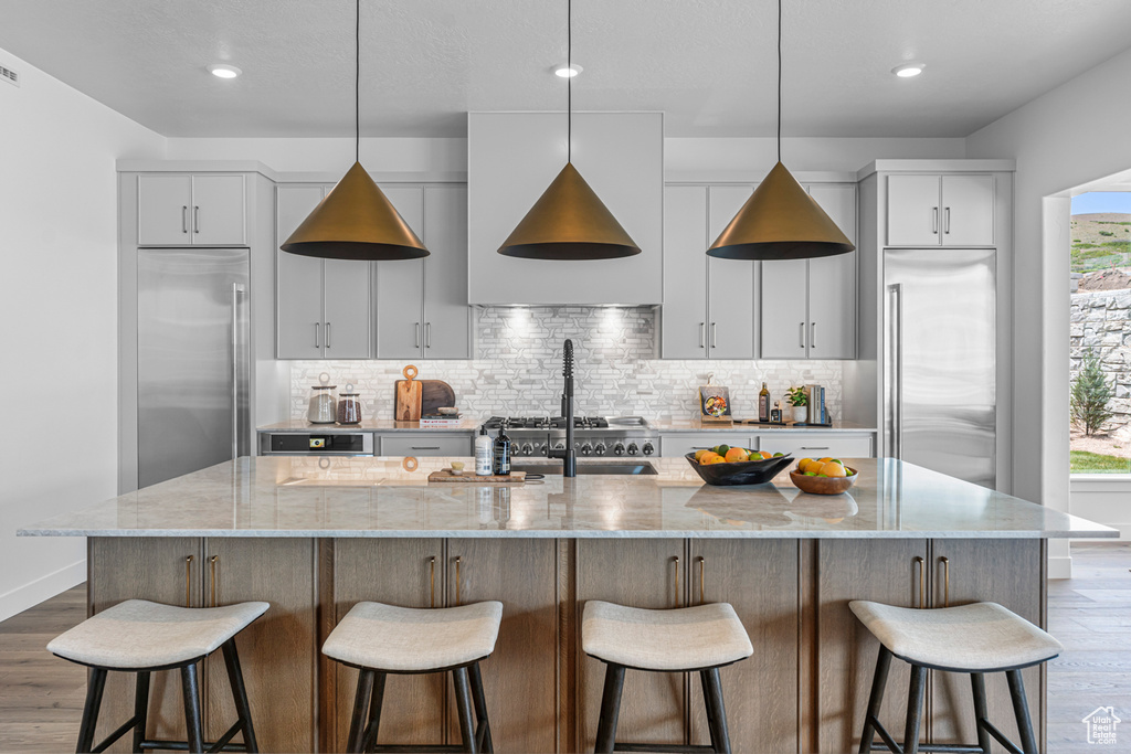 Kitchen with built in fridge, wood finished floors, decorative backsplash, white cabinetry, and recessed lighting