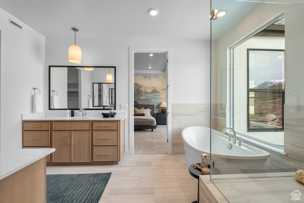 Full bath featuring vanity, a freestanding bath, and ensuite bathroom