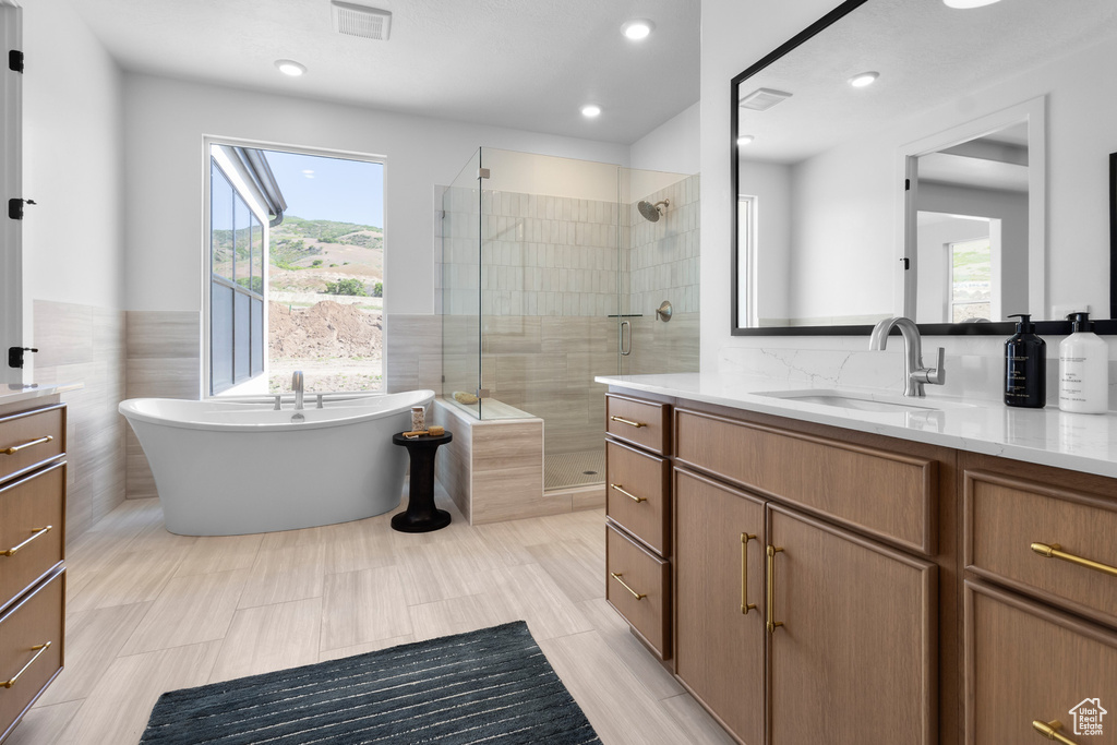 Bathroom featuring vanity, a stall shower, a soaking tub, and recessed lighting