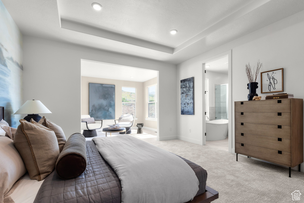 Bedroom with light carpet, a raised ceiling, recessed lighting, and connected bathroom
