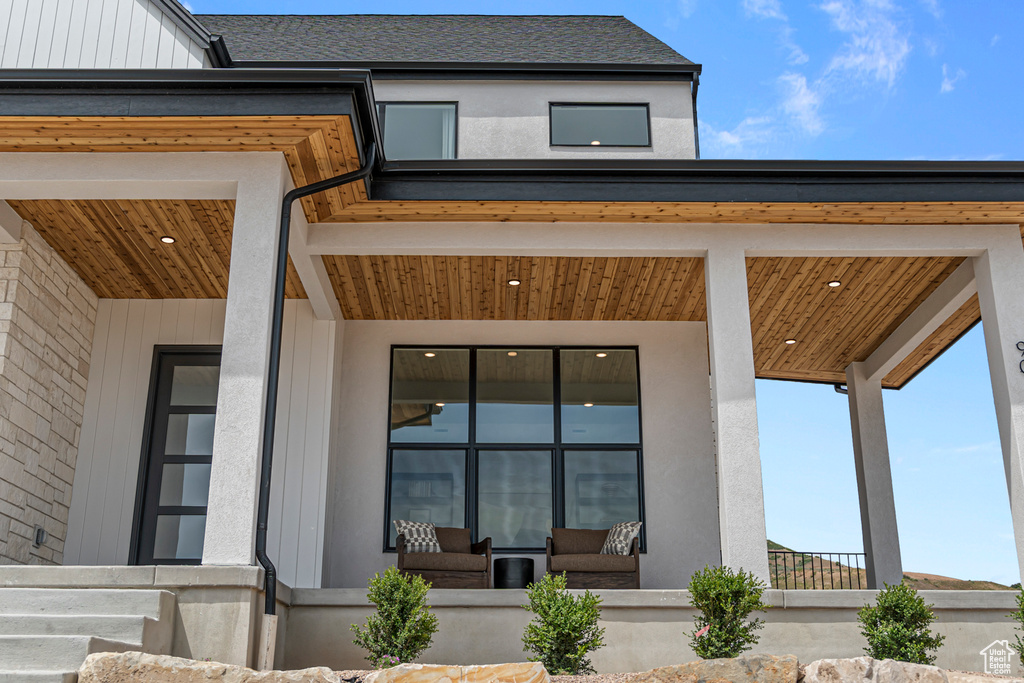 Doorway to property featuring a porch and a shingled roof