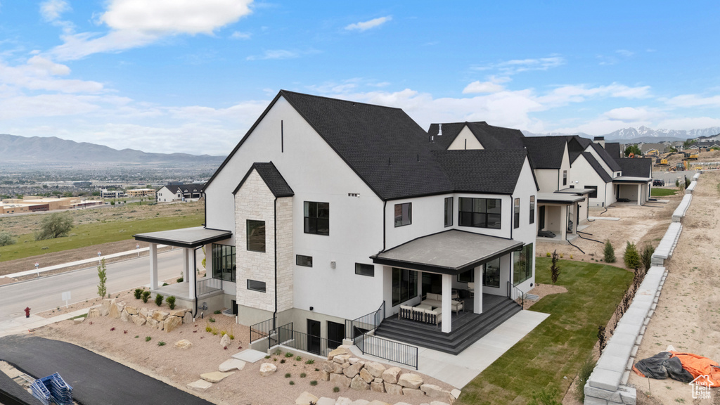 Rear view of property featuring a mountain view, a shingled roof, and stucco siding