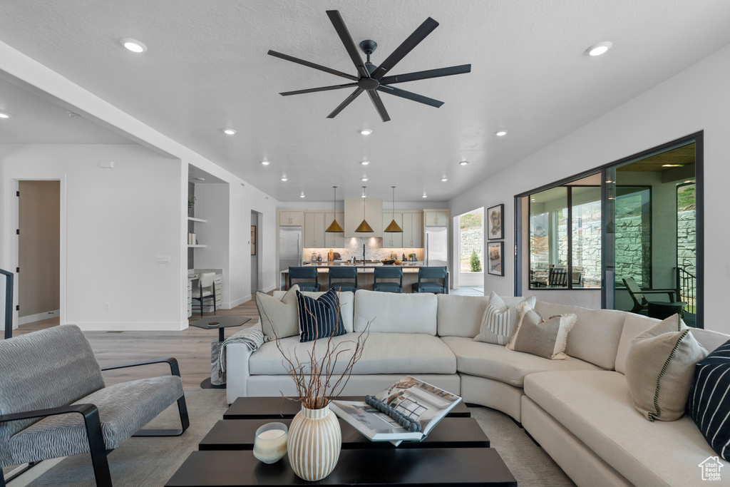 Living room featuring recessed lighting, plenty of natural light, a ceiling fan, and light wood finished floors