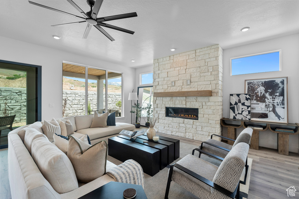 Living room featuring a stone fireplace, wood finished floors, recessed lighting, and a ceiling fan