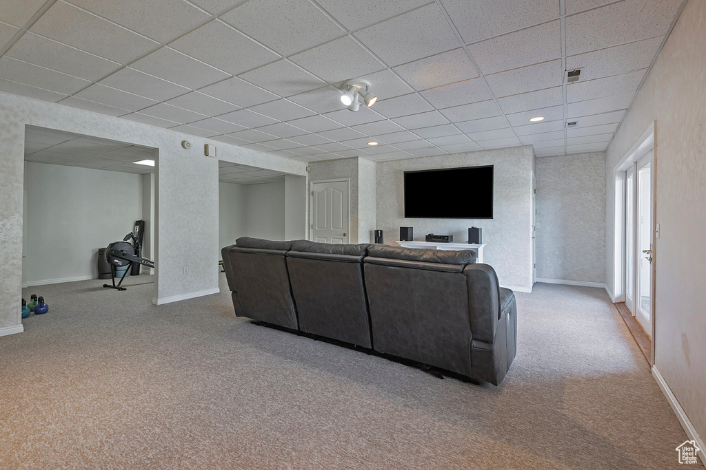 Carpeted living room featuring a drop ceiling and baseboards