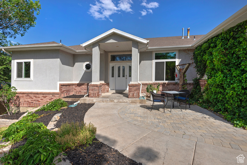 View of front of house with brick siding, stucco siding, and a patio