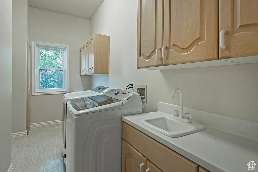 Laundry room featuring separate washer and dryer, cabinet space, and light flooring