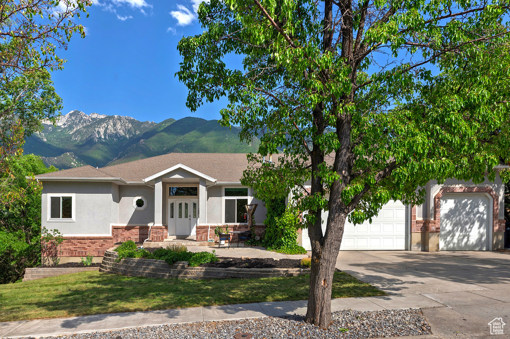 View of front of house featuring stucco siding, concrete driveway, a mountain view, and brick siding