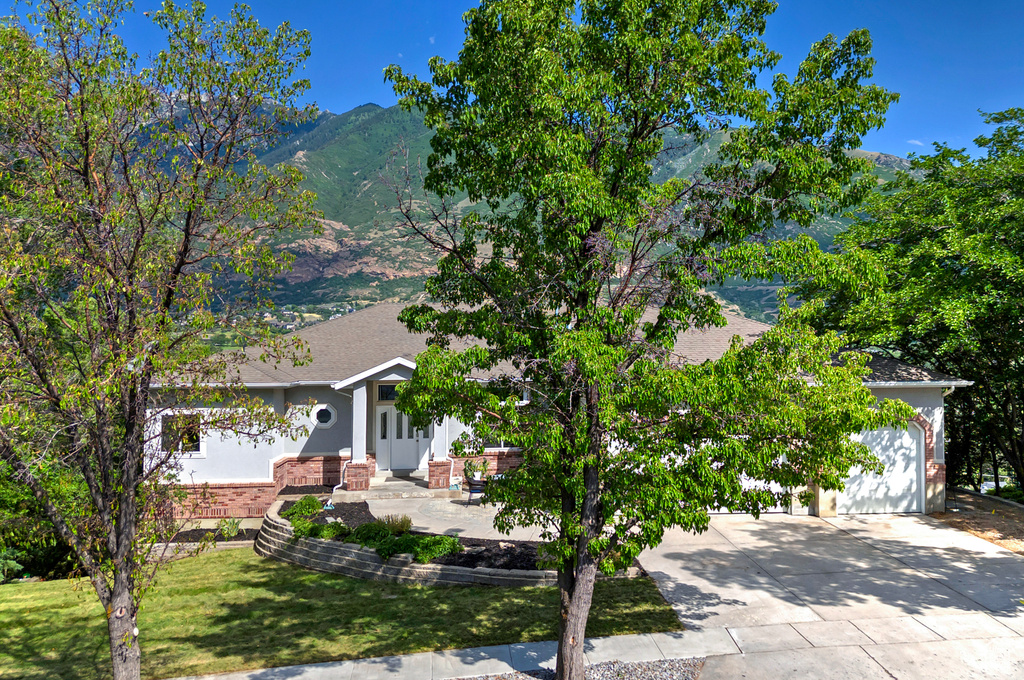 Obstructed view of property with driveway, a garage, a mountain view, brick siding, and a front lawn