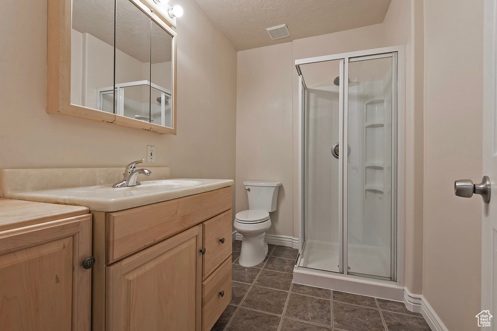 Full bathroom featuring a stall shower, vanity, and a textured ceiling