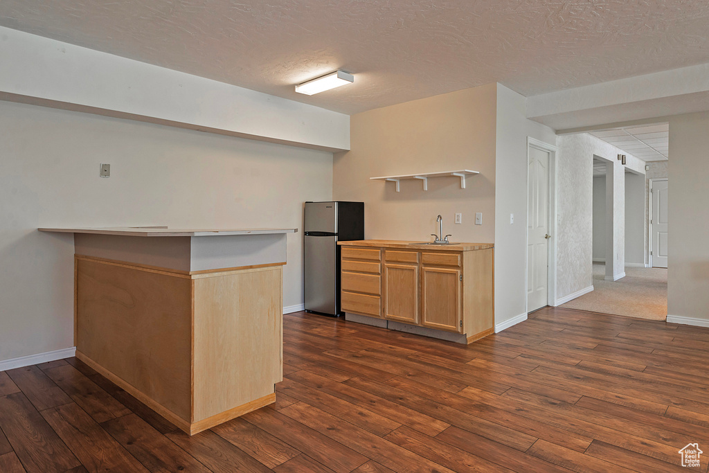 Kitchen featuring freestanding refrigerator, open shelves, dark wood-style flooring, a textured ceiling, and light countertops