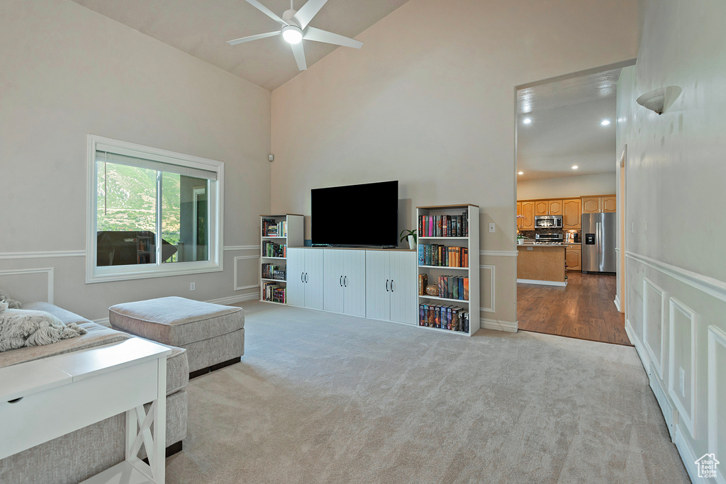 Carpeted living area with ceiling fan, high vaulted ceiling, and recessed lighting
