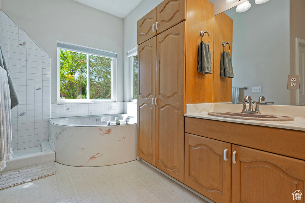 Full bath featuring vanity, a bath, and tile patterned floors