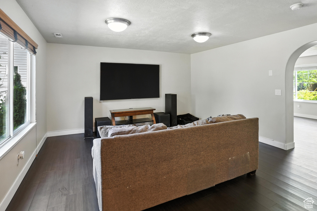Living area with arched walkways and dark wood finished floors