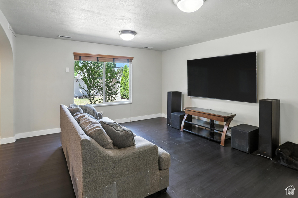 Living room with arched walkways, wood finished floors, and a textured ceiling