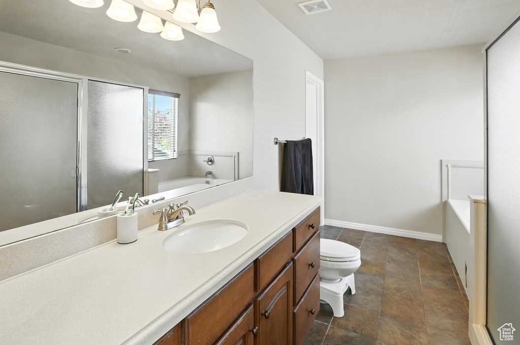 Full bath featuring a garden tub, a stall shower, vanity, a chandelier, and stone finish flooring
