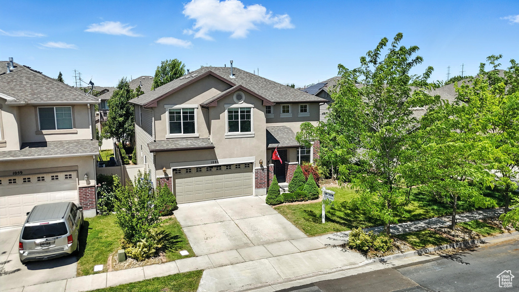 Traditional-style house featuring stucco siding, driveway, an attached garage, brick siding, and roof with shingles