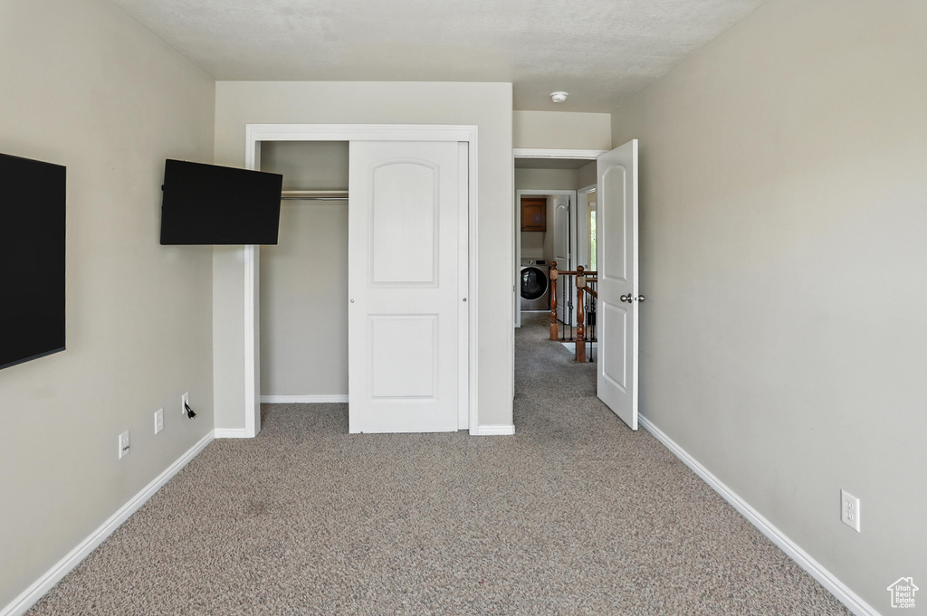 Unfurnished bedroom with washer / clothes dryer, carpet floors, and a closet