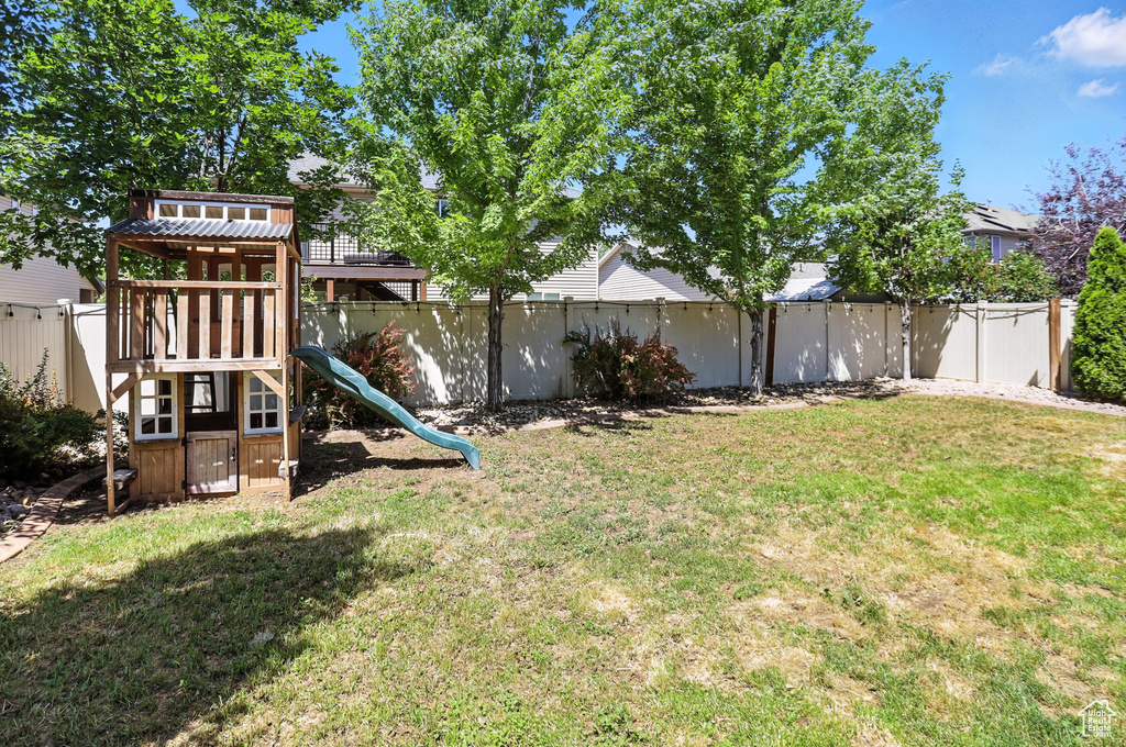 Fenced backyard featuring a playground