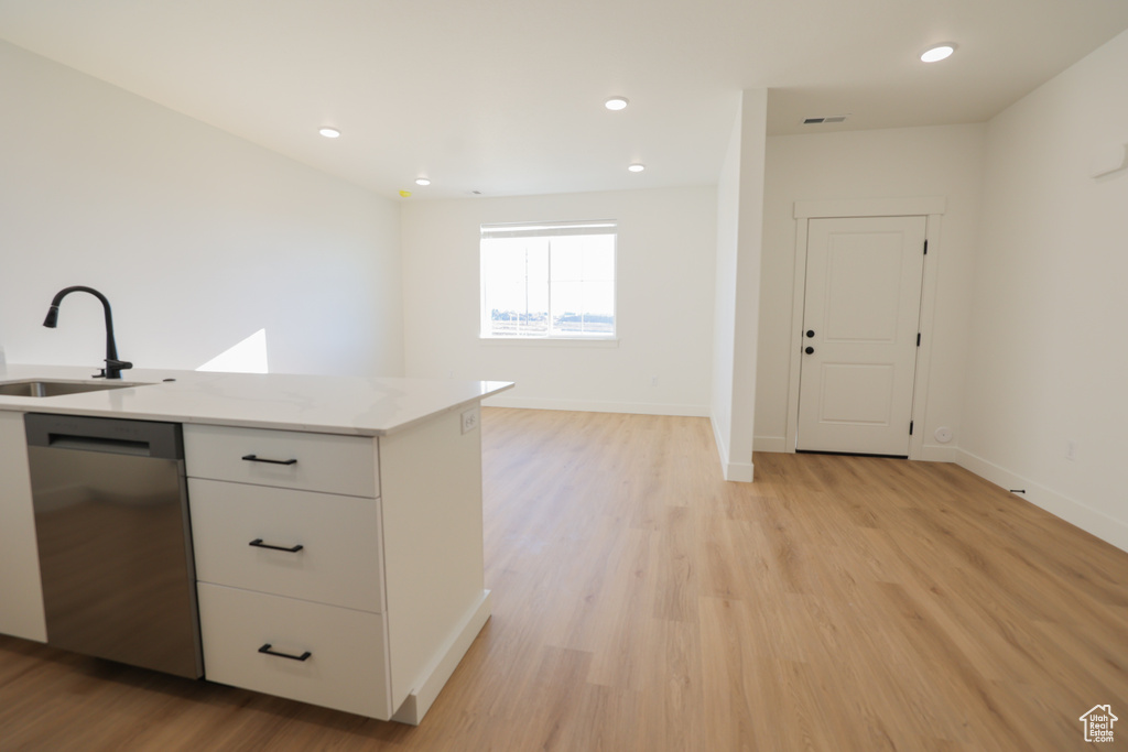Kitchen featuring stainless steel dishwasher, open floor plan, light wood-style flooring, white cabinetry, and recessed lighting