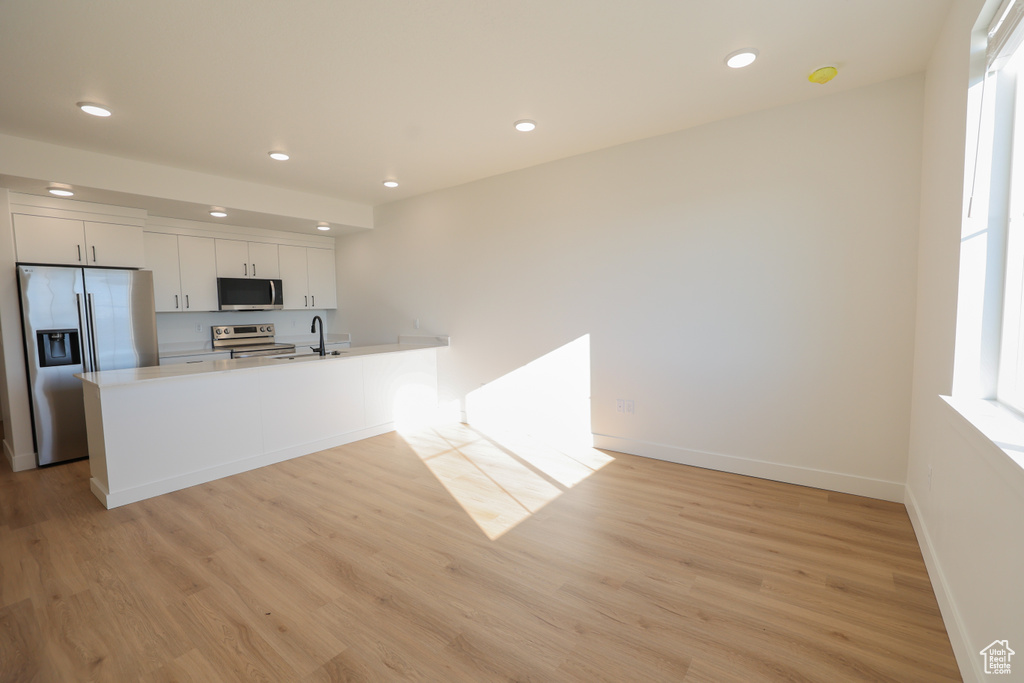 Kitchen with appliances with stainless steel finishes, recessed lighting, light wood-style floors, white cabinetry, and light countertops