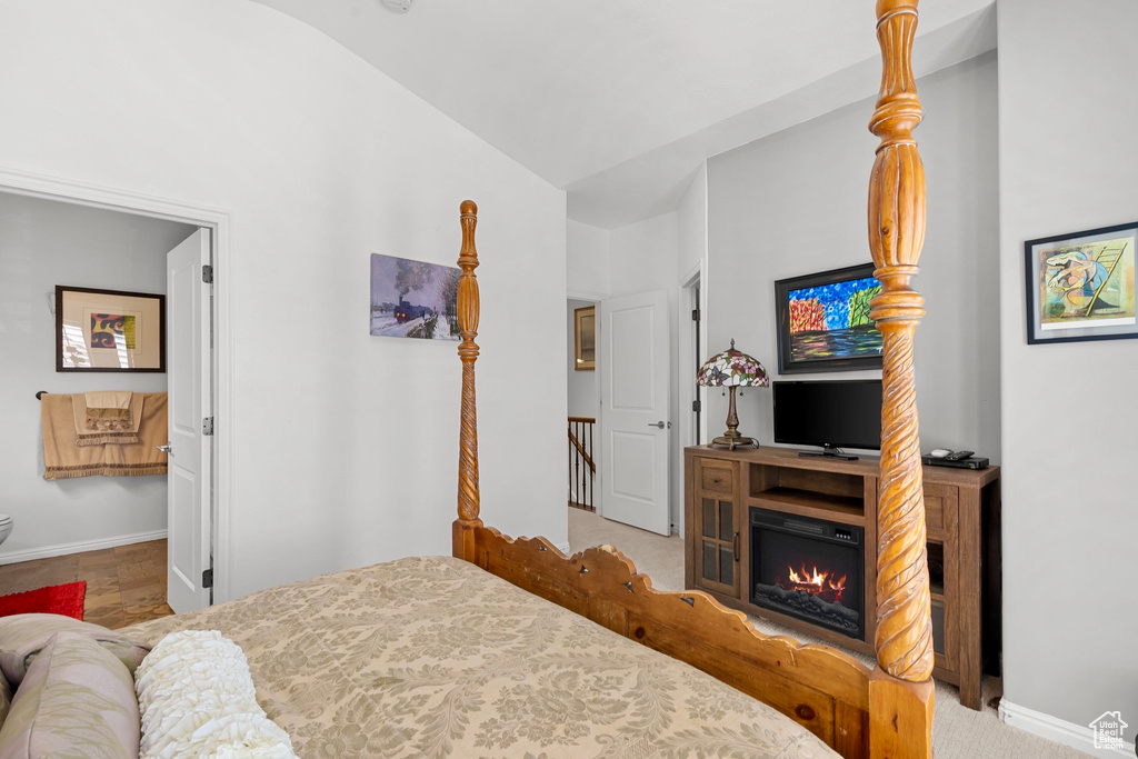 Bedroom featuring lofted ceiling and a glass covered fireplace