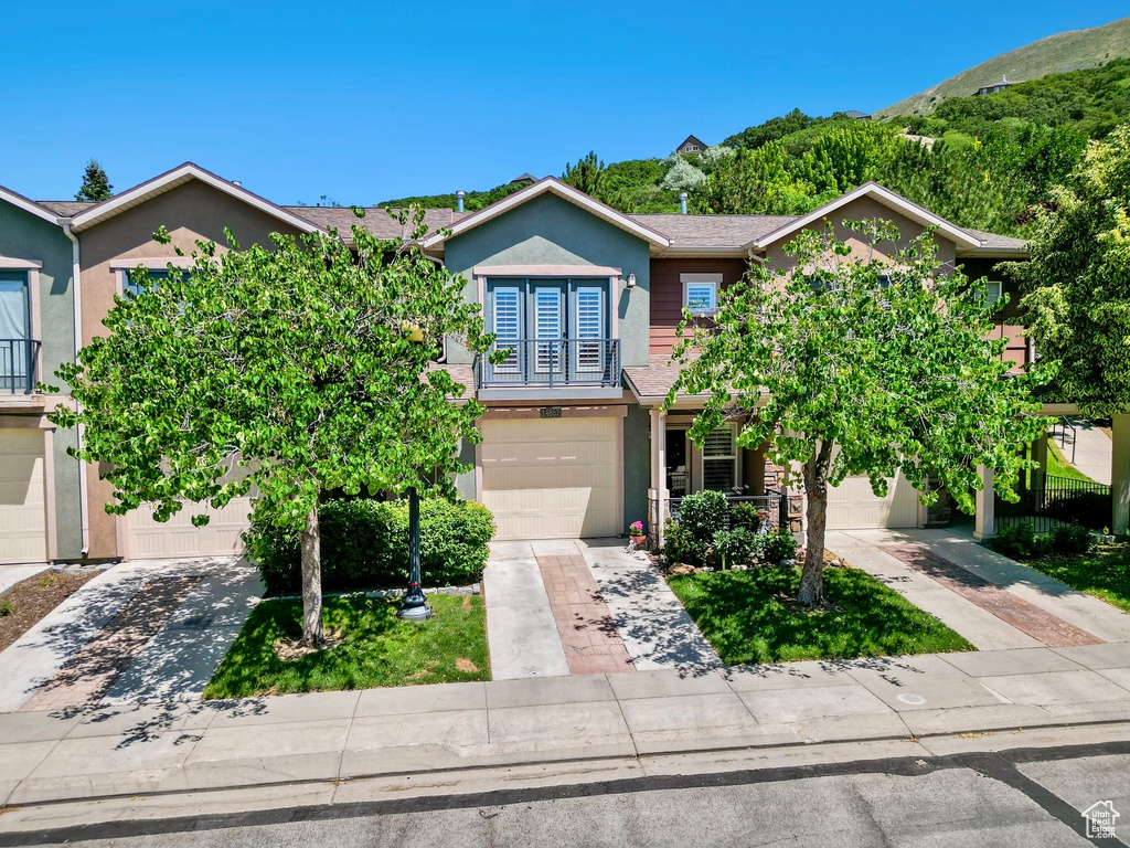View of front facade featuring driveway, stucco siding, and a garage