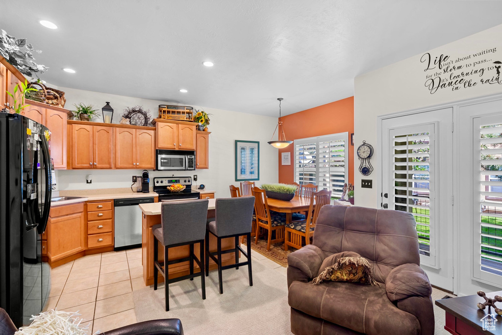 Kitchen featuring stainless steel appliances, light countertops, open floor plan, a breakfast bar, and decorative light fixtures