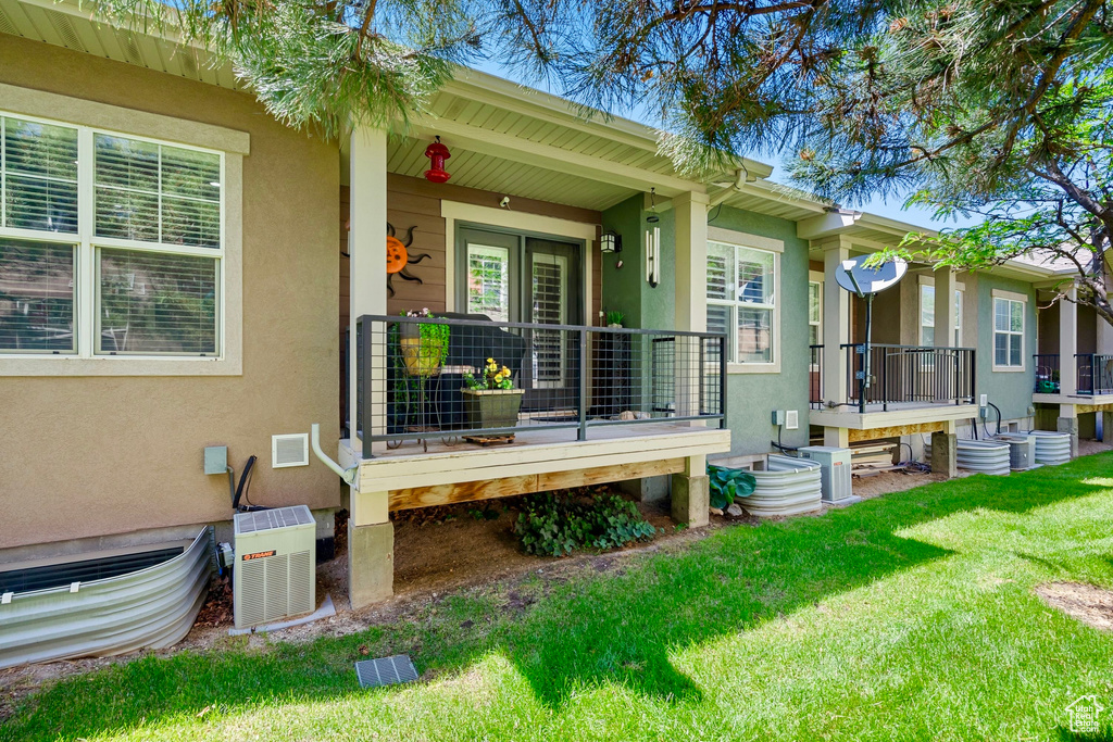 View of exterior entry with stucco siding, a lawn, and a porch