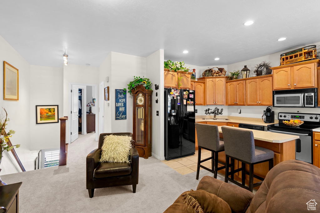 Kitchen featuring stainless steel appliances, light countertops, open floor plan, a kitchen bar, and recessed lighting