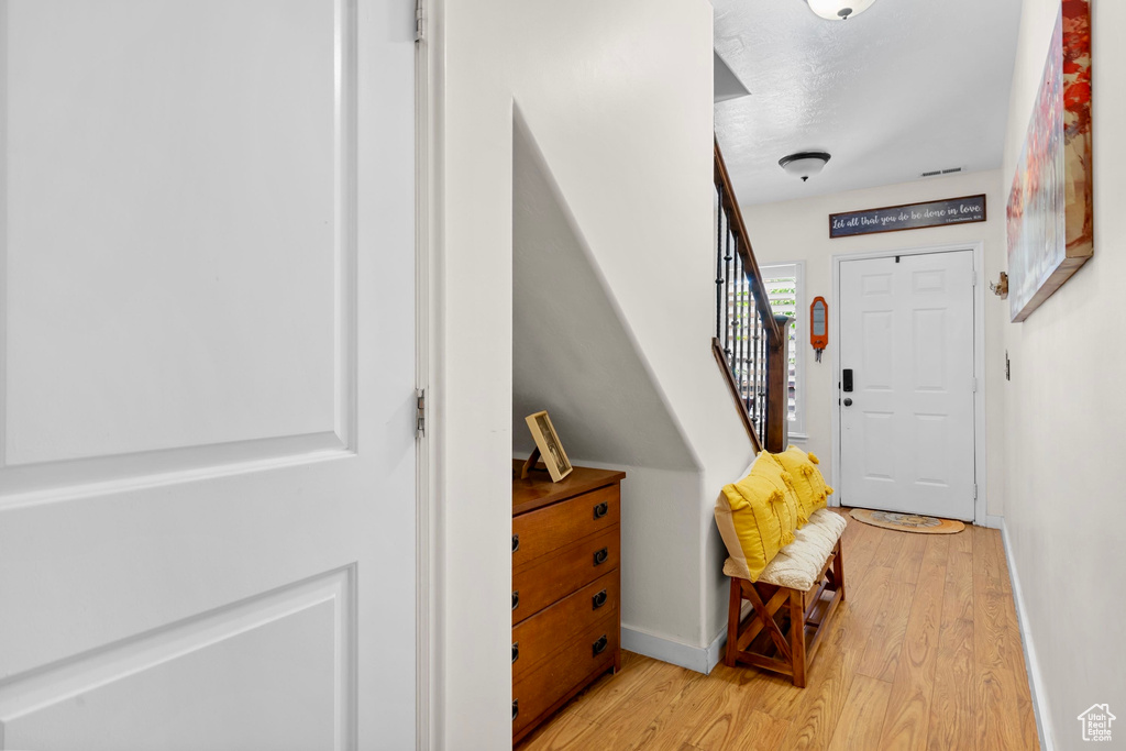 Foyer with light wood-style flooring and stairs