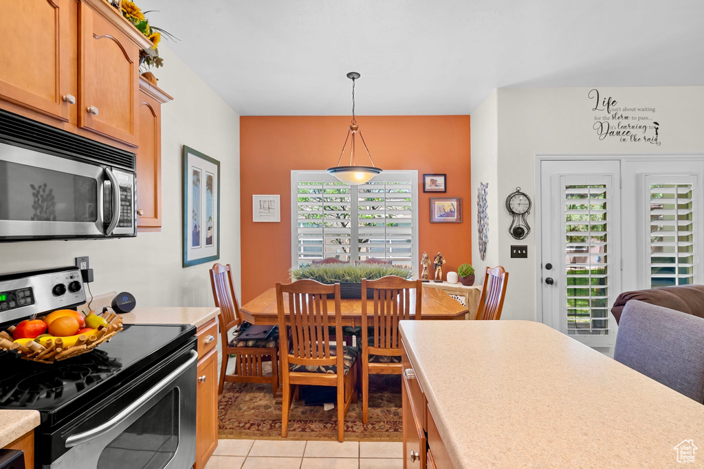 Kitchen featuring stainless steel appliances, light countertops, decorative light fixtures, and light tile patterned floors