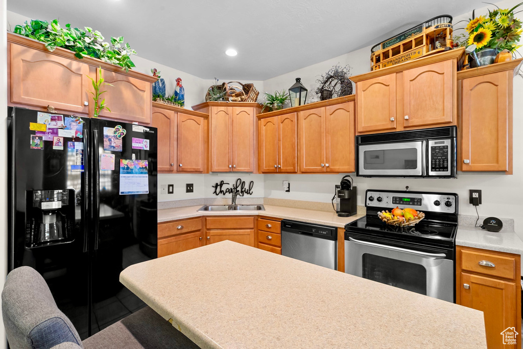 Kitchen featuring stainless steel appliances, light countertops, a breakfast bar, and recessed lighting