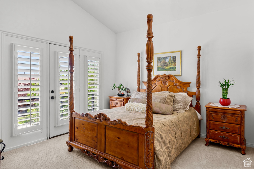 Bedroom with access to exterior, light carpet, and vaulted ceiling